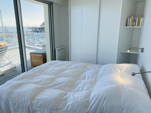 Cette chambre comprend un lit blanc et une grande fenêtre. dans l'établissement ATLANTIQUE 2 - Belle terrasse, Vue mer - TAT19, à Carnac