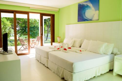 a bedroom with a large white bed with flowers on it at Refúgios Parajuru in Parajuru