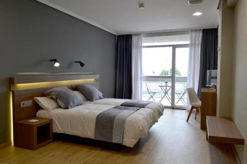 1 dormitorio con 1 cama grande y balcón en Hotel Alda Sada Marina en Sada