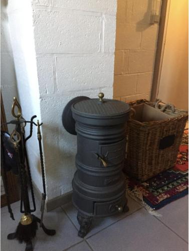 a black stove sitting next to a white brick wall at La Chênaie in Vresse-sur-Semois
