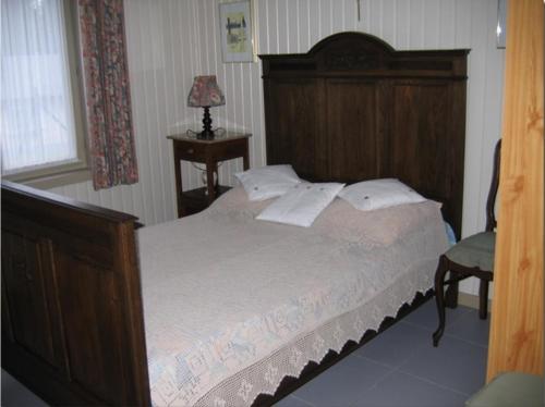 een slaapkamer met een groot bed met een houten hoofdeinde bij La Chênaie in Vresse-sur-Semois