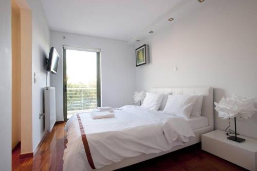 - une chambre blanche avec un grand lit et une fenêtre dans l'établissement Voula, A modern, minimal and stylish, apartment, à Athènes