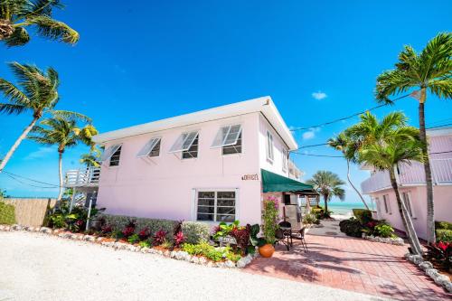 a white house on the beach with palm trees at Rainbow Bend Resort in Marathon
