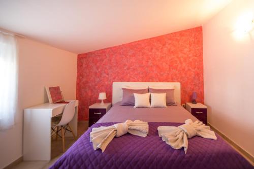 ein Schlafzimmer mit einem lila Bett mit zwei Handtüchern darauf in der Unterkunft Apartments Kovačević in Petrovac na Moru