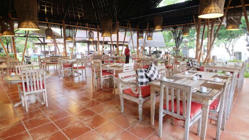 a dining room with wooden tables and chairs at Taman Sari Bali Resort and Spa in Pemuteran