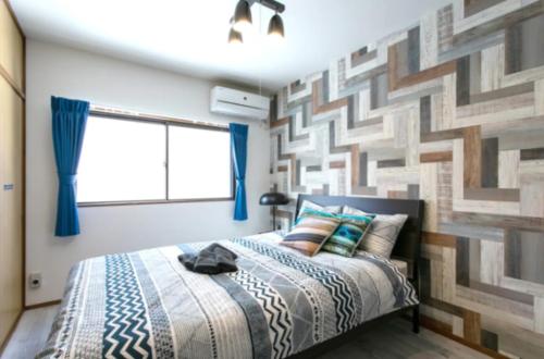 a bedroom with a bed with a geometric wall at Secret House - 2 min to FuSe station - in Osaka
