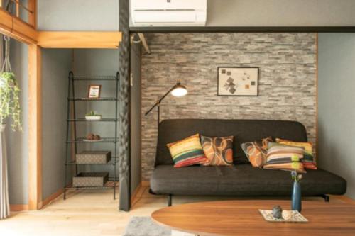 a living room with a couch and a brick wall at Secret House - 2 min to FuSe station - in Osaka