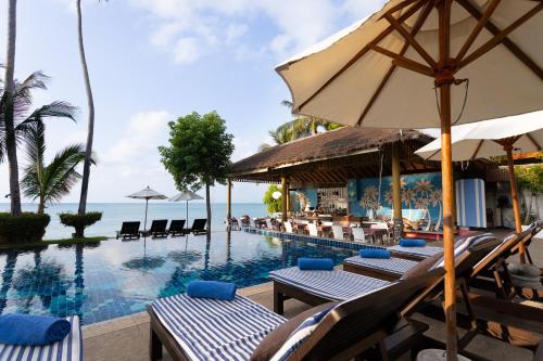 a pool at a resort with chairs and an umbrella at Palm Coco Mantra in Lamai
