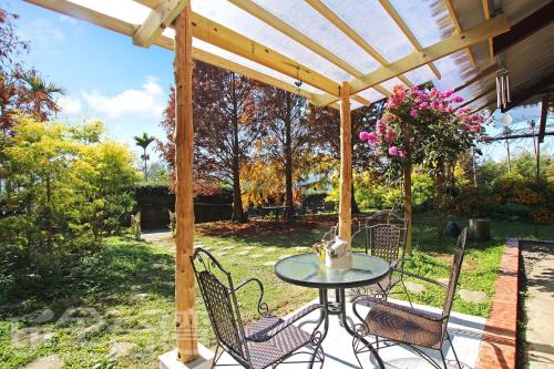 a patio with a table and chairs under a wooden pergola at 朵麗絲森林 in Meishan
