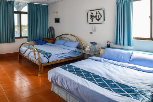 2 camas en una habitación con cortinas azules en 東石愛琴海藝宿文旅 合法民宿272, en Ting-liao
