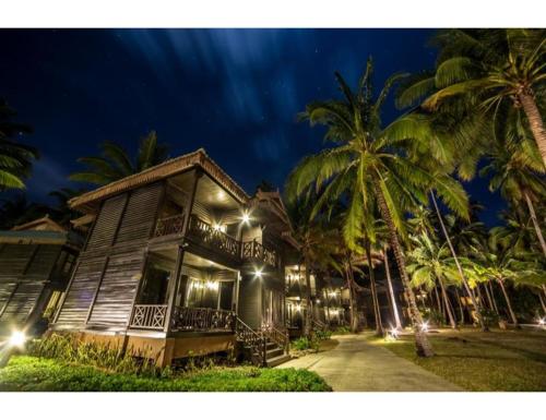 a wooden house with palm trees in the night at The Taaras Beach & Spa Resort in Redang Island