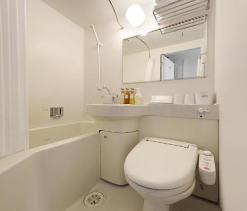a white bathroom with a toilet and a sink at Keio Presso Inn Tokyo Kudanshita in Tokyo
