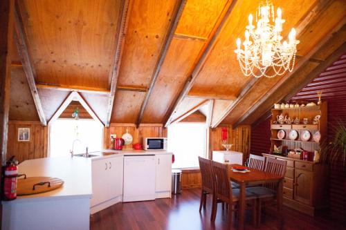 una cucina con soffitti in legno, lampadario pendente e tavolo di Barossa Barn Bed and Breakfast ad Angaston