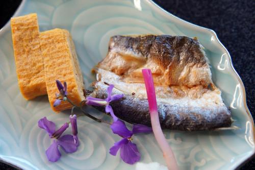 a plate with a piece of meat and bread and purple flowers at IKI RETREAT by Onko Chishin in Iki