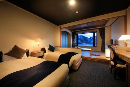 a hotel room with two beds and a desk and a window at Yutorelo Nikko in Nikko