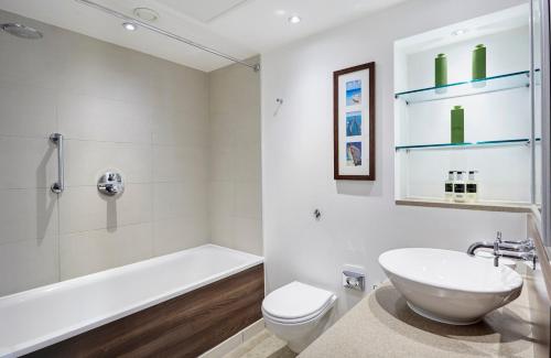 a bathroom with a sink and a tub and a toilet at Staybridge Suites Newcastle by IHG in Newcastle upon Tyne