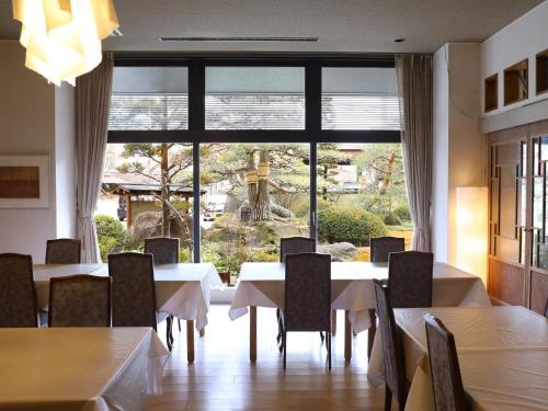 a dining room with tables and chairs and a large window at Kamiyamada Hotel in Chikuma