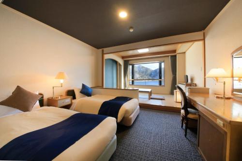 a hotel room with two beds and a desk at Yutorelo Nikko in Nikko