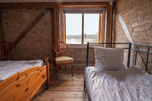 Zimmer mit 2 Betten, einem Stuhl und einem Fenster in der Unterkunft Kanalmagasinets Pensionat in Söderköping