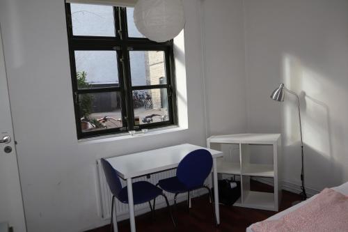 um quarto com uma secretária, 2 cadeiras e uma janela em Charming Red Courtyard Apartment em Copenhague