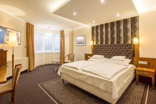 a hotel room with a large bed and a television at Szőnyi Garden Hotel Pest in Budapest