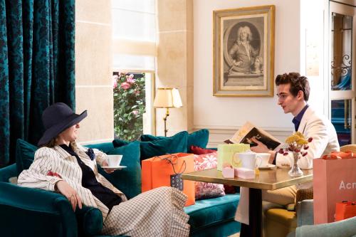 Un uomo e una donna seduti in un soggiorno di Odeon Hotel by Malone a Parigi