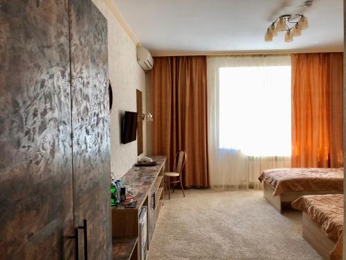 Habitación de hotel con cama, escritorio y TV. en Flamingo, en Aktobe