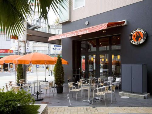 an outdoor patio with tables and chairs and umbrellas at Hotel Hillarys in Osaka