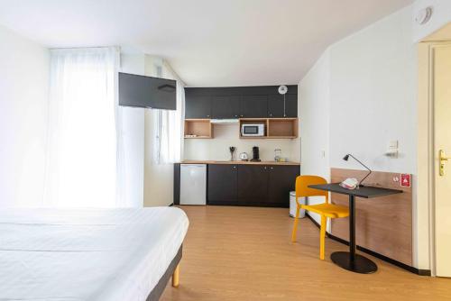 a bedroom with a bed and a desk and a kitchen at Apparthotel Le Hüb Grenoble in Grenoble