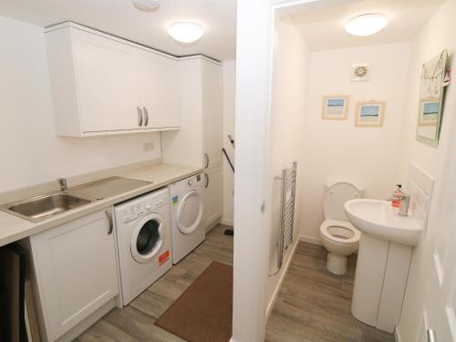 a white bathroom with a sink and a washing machine at Lake View Cottage in Rhosneigr