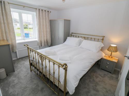 Un dormitorio con una gran cama blanca y una ventana en Lake View Cottage, en Rhosneigr