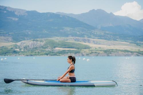 a woman sitting on a paddle board in the water at Hotel la Robeyere; BW Signature Collection in Embrun