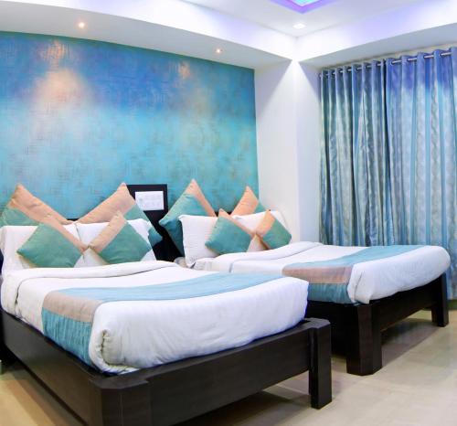 two beds in a room with a painting on the wall at Aishwarya Le Royal in Mysore