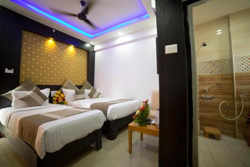 two beds in a hotel room with a purple ceiling at Aishwarya Le Royal in Mysore