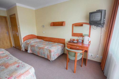 a hotel room with a desk and a bed and a television at Geovita Muszyna in Muszyna