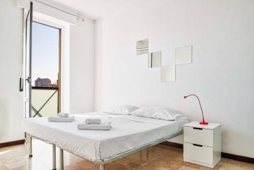 una camera bianca con un letto e una finestra di LUVI - Alzaia Naviglio Pavese a Milano