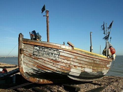 um velho barco de madeira sentado na praia em Dunkerley's Hotel and Restaurant em Deal