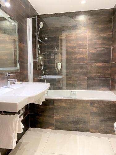 a bathroom with a sink and a bath tub at Hôtel Edouard 6 by Malone in Paris
