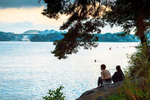 two people sitting on a rock near a body of water at Skanstulls Boutique Hostel in Stockholm