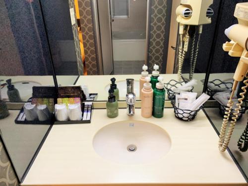 Hotel NewMie (Adult Only) في طوكيو: منضدة الحمام مع الحوض أمام المرآة