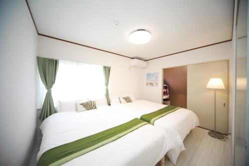 a bedroom with a large white bed and a window at Higashiomi Large House in Higashiomi