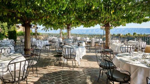 a group of tables and chairs with white tables and trees at Airelles Gordes, La Bastide in Gordes