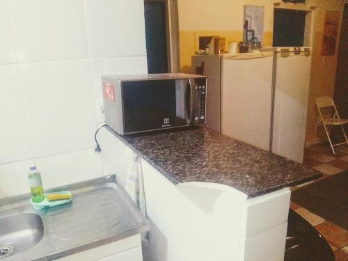 a kitchen with a counter with a microwave and a refrigerator at Morada BemTeVi Guest House in São José dos Campos