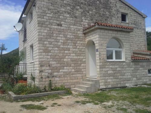 a brick house with a window and stairs on it at Mate in Zagvozd