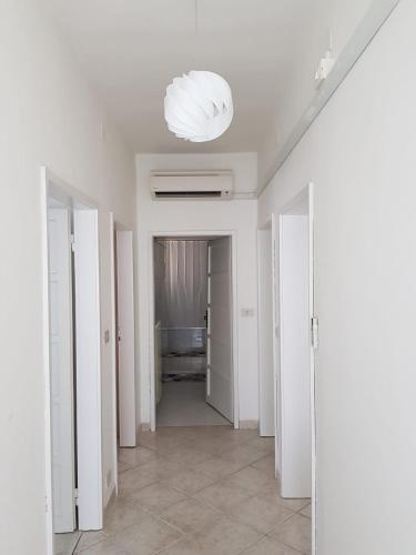 un corridoio con pareti bianche e lampadario; di CASAWHITE a Cavallino-Treporti