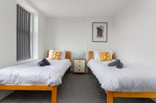 two twin beds in a room with a window at Heritage House Apartments - Blackpool Resort Collection in Blackpool