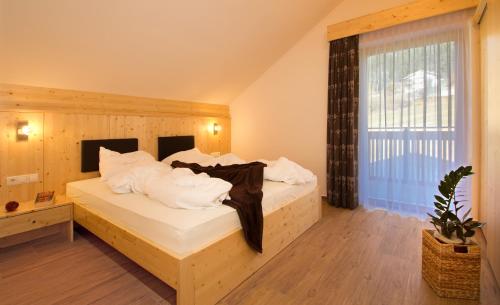 a bedroom with a bed with white sheets and a window at Stiflerhof in Falzes