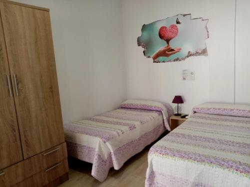 1 dormitorio con 2 camas y un corazón en la pared en Hostal la Campa, en Chiclana de la Frontera