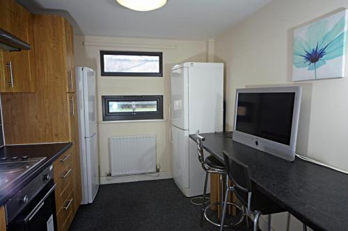 a kitchen with a desk with a tv and a refrigerator at Trigg Hall in Bradford