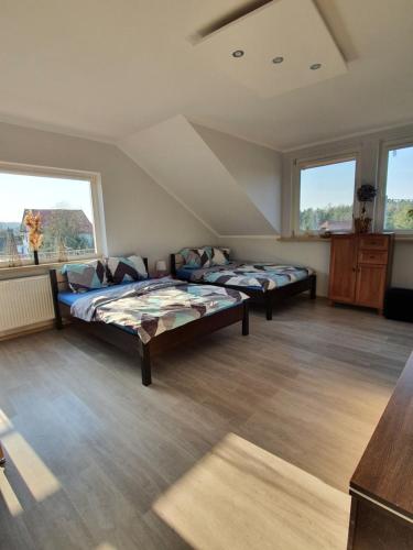 two beds in a large room with two windows at Słoneczna Przystań in Kruklanki